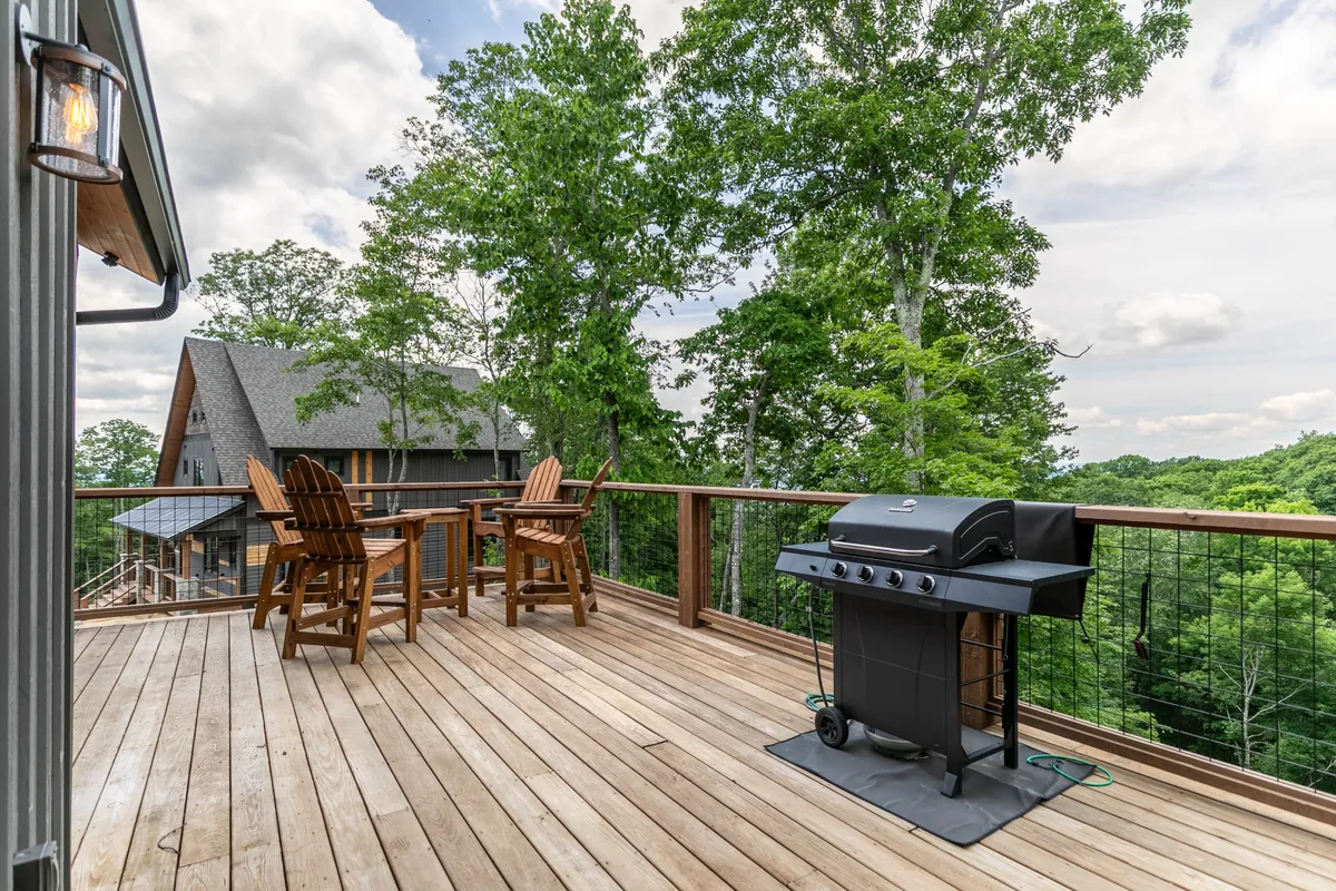 An exterior dining area featuring a grill and table set amongst towering trees, ideal for outdoor meals and gatherings in the fresh mountain air.