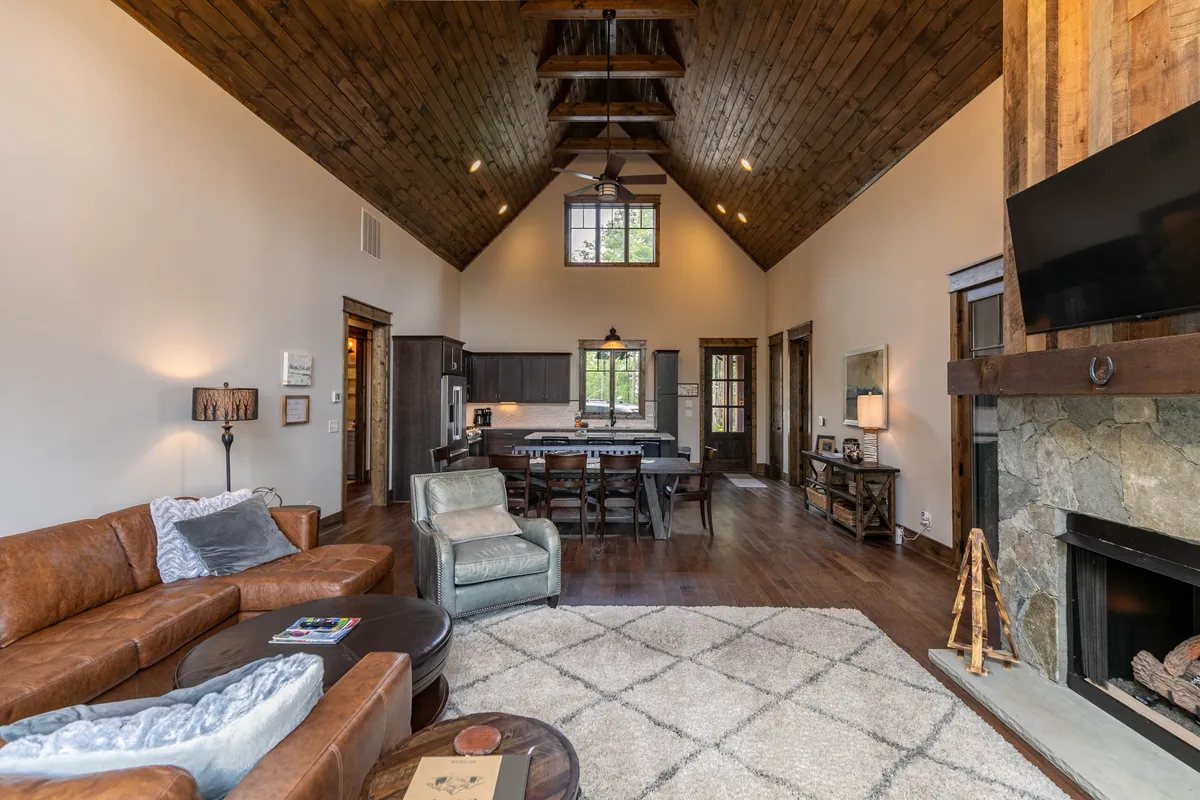 A warm, welcoming space with a sofa, dining table, and a fireplace, accented by large windows that deliver plenty of natural light. The layout encourages communal activities, from group meals to relaxing by the fire.