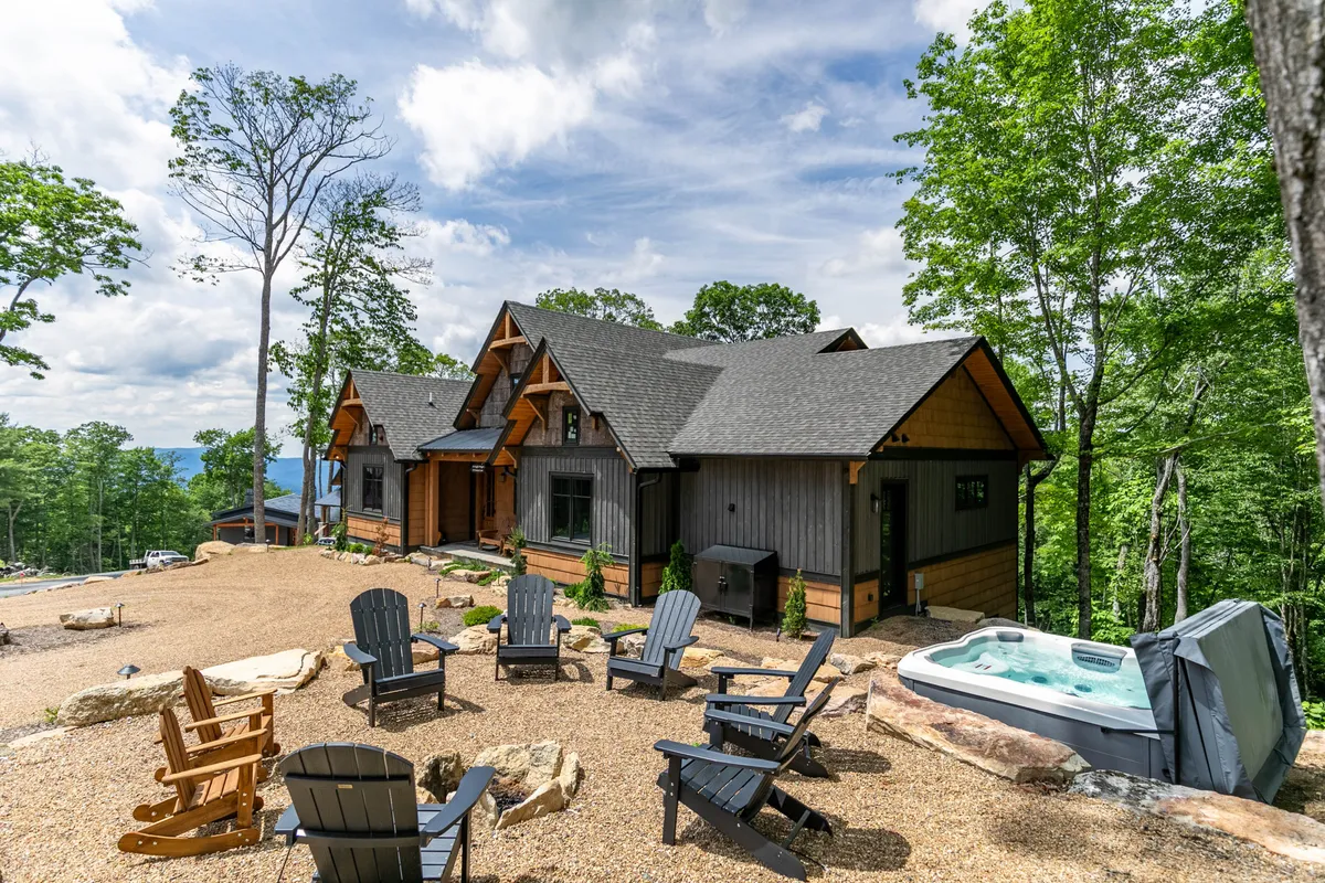 An exterior view featuring the house's private hot tub and an inviting seating area, all set against a tranquil backdrop of nature. The hot tub is front and center, with ample space for relaxation and opportunities for stargazing or soaking after a day of adventure.