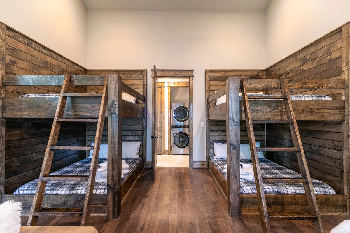 A playful bunk room with sturdy bunk beds and a visible laundry area. The inviting space is designed for fun and togetherness, with enough room for sleepovers and social activities. The cheerful mood hints at the presence of games or amenities for younger guests.